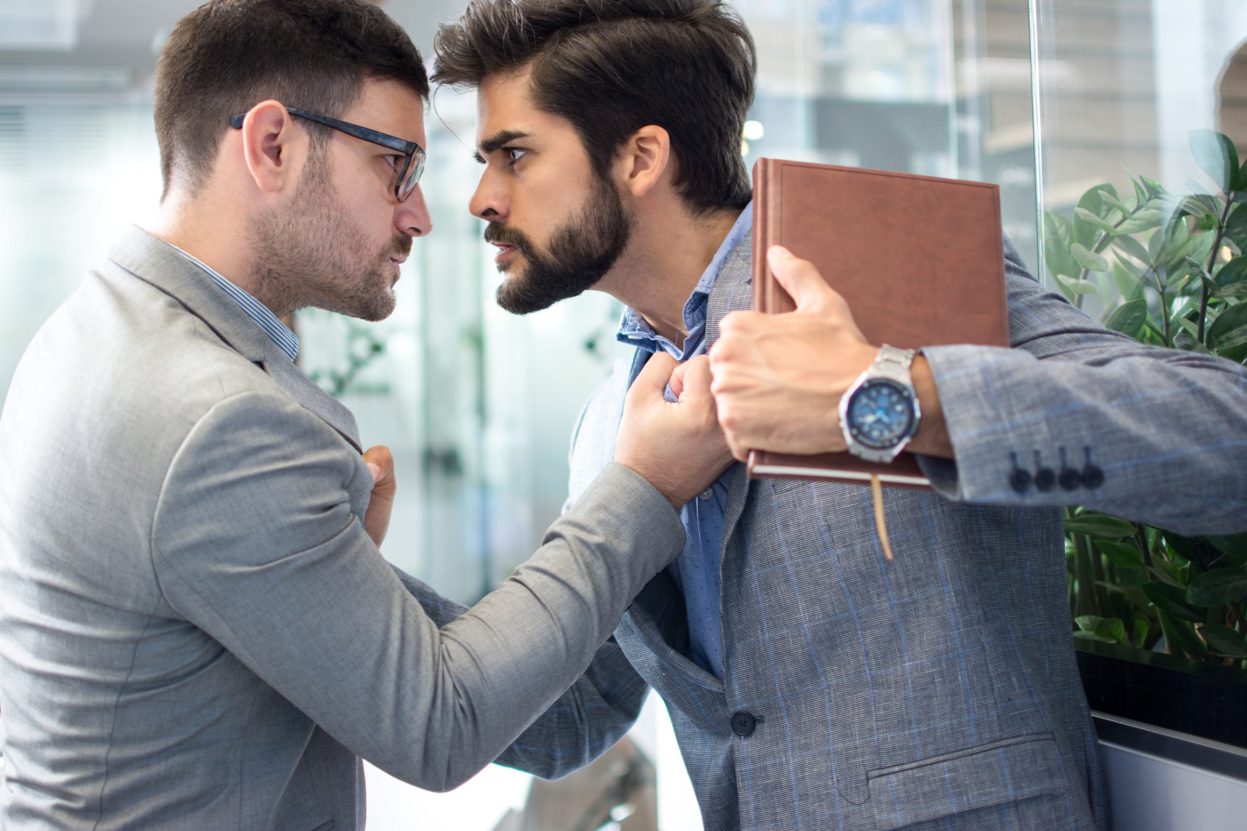 Business conflict between two business men in formal-wear in office. Boss and employee with aggressive expression fight. Gérer les personnalités difficiles dans l’entreprise